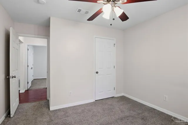 an empty room with a chandelier fan and closet