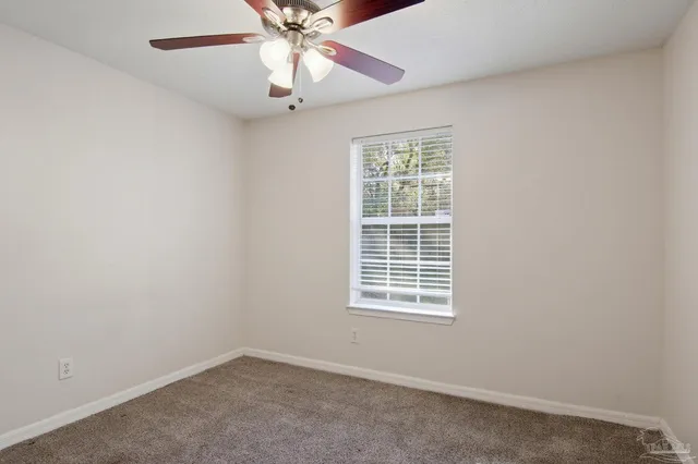 an empty room with a window and a fan