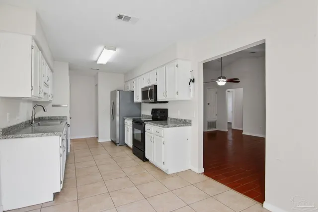 a kitchen with a refrigerator sink and white cabinets