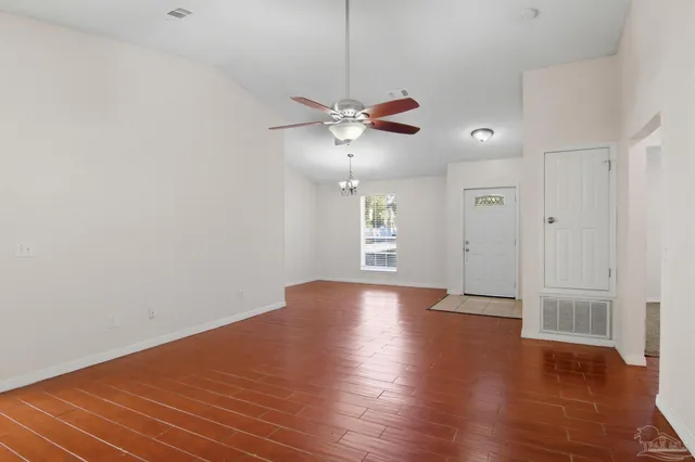 a view of an empty room with window and wooden floor