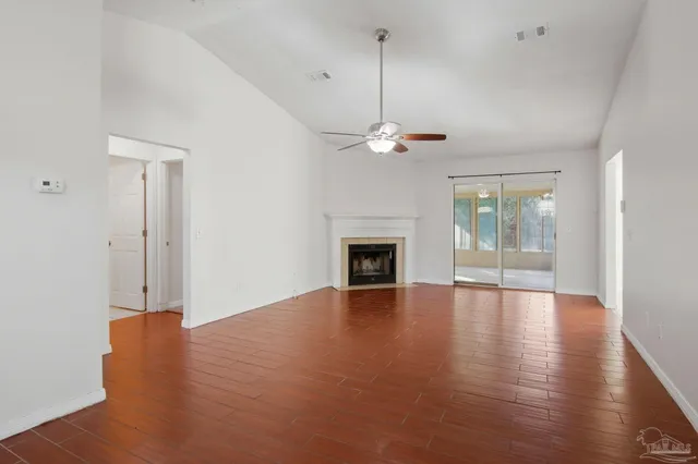 a view of an empty room with wooden floor fireplace and a window