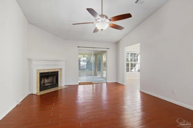 an empty room with wooden floor fireplace and windows