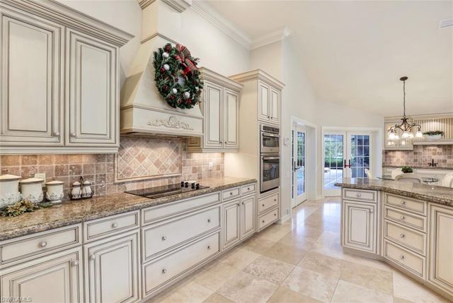 a kitchen with white cabinets and chandelier