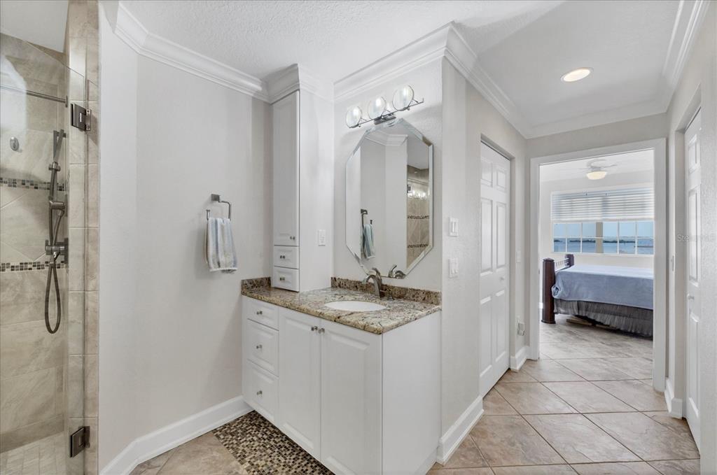 13313 Gasparilla Road, Unit C401 Placida, FL 33946 - Photo 17 of 30 a bathroom with a granite countertop sink a mirror and a shower
