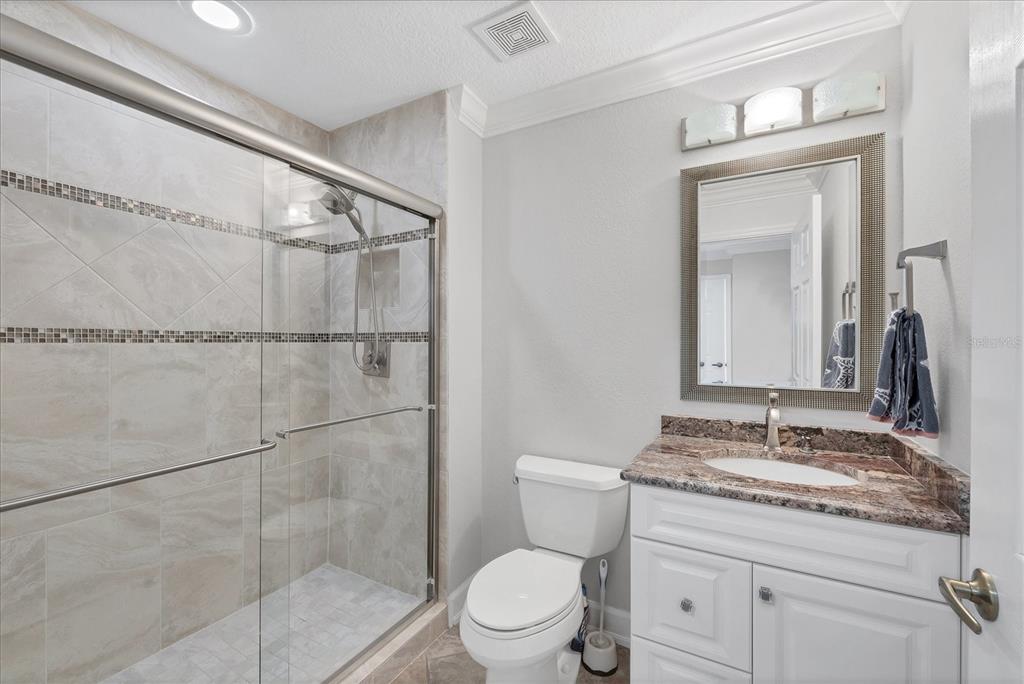 13313 Gasparilla Road, Unit C401 Placida, FL 33946 - Photo 20 of 30 a bathroom with a granite countertop sink toilet mirror and shower