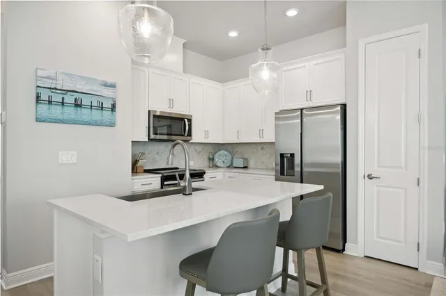 a kitchen with stainless steel appliances a refrigerator a stove a sink a dining table and chairs