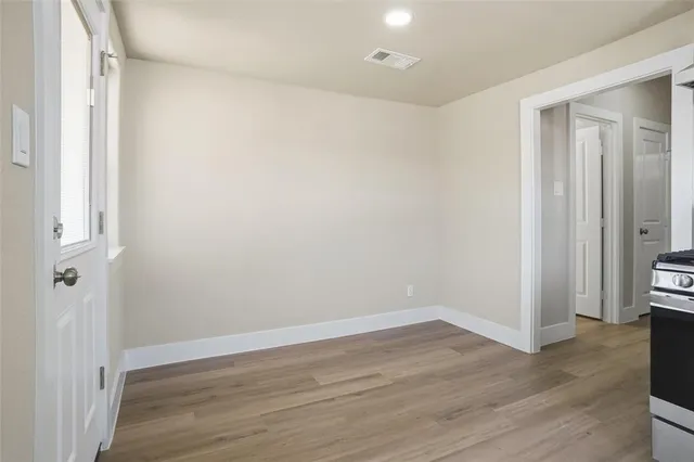 a view of an empty room with wooden floor and a bathroom