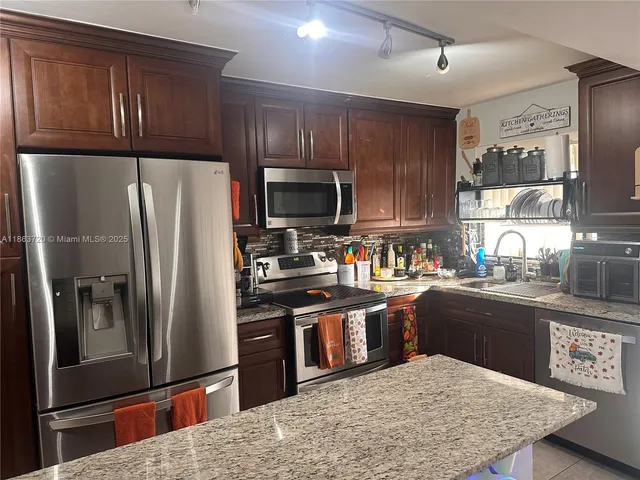 a kitchen with granite countertop wooden cabinets a refrigerator and a sink