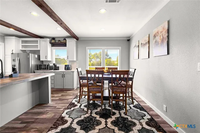 a dining hall with stainless steel appliances granite countertop a stove a sink a dining table and chairs