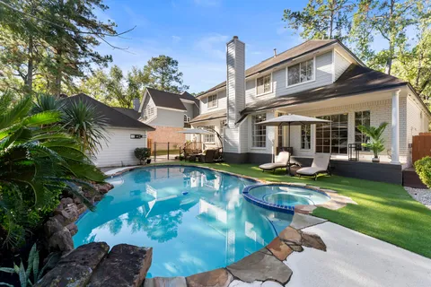 a view of a house with swimming pool lawn chairs and a yard