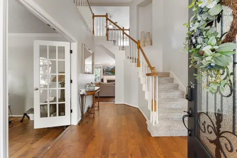 a view of a hallway with wooden floor and staircase