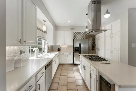 a large white kitchen with stainless steel appliances a sink a stove and a refrigerator