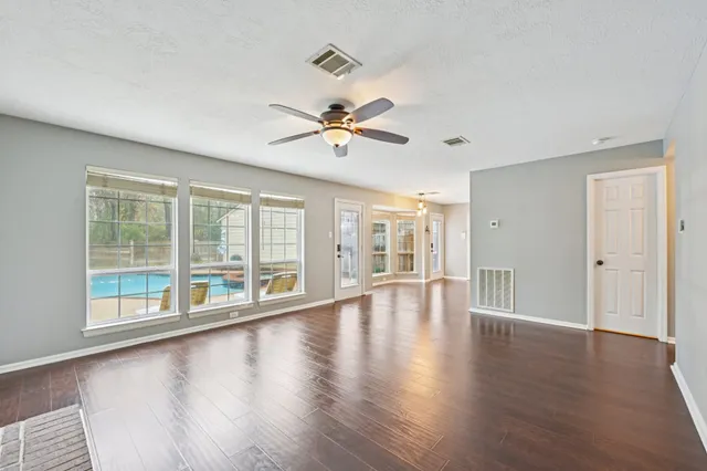 a view of an empty room with window and wooden floor
