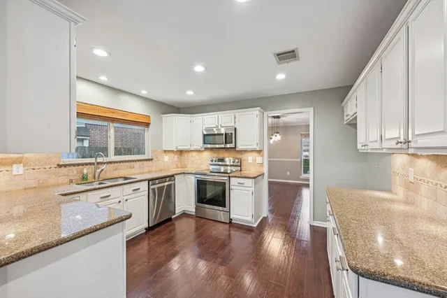 a large kitchen with stainless steel appliances granite countertop a lot of counter space and wooden floors
