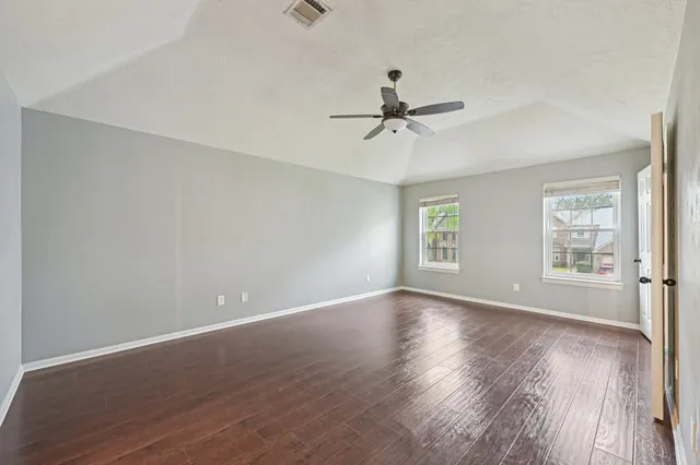a view of empty room with wooden floor and fan