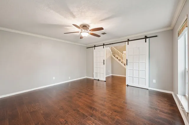 an empty room with wooden floor ceiling fan and windows