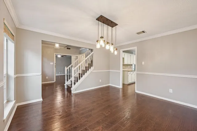 a hallway with wooden floor chandelier and entryway