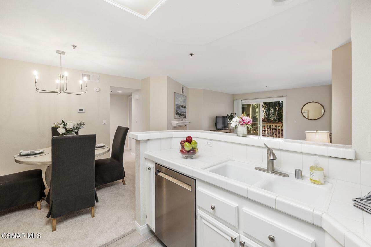 697 Sutton Crest Trail, Unit 302 Oak Park, CA 91377 - Photo 11 of 47 a kitchen with stainless steel appliances kitchen island a table and chairs in it
