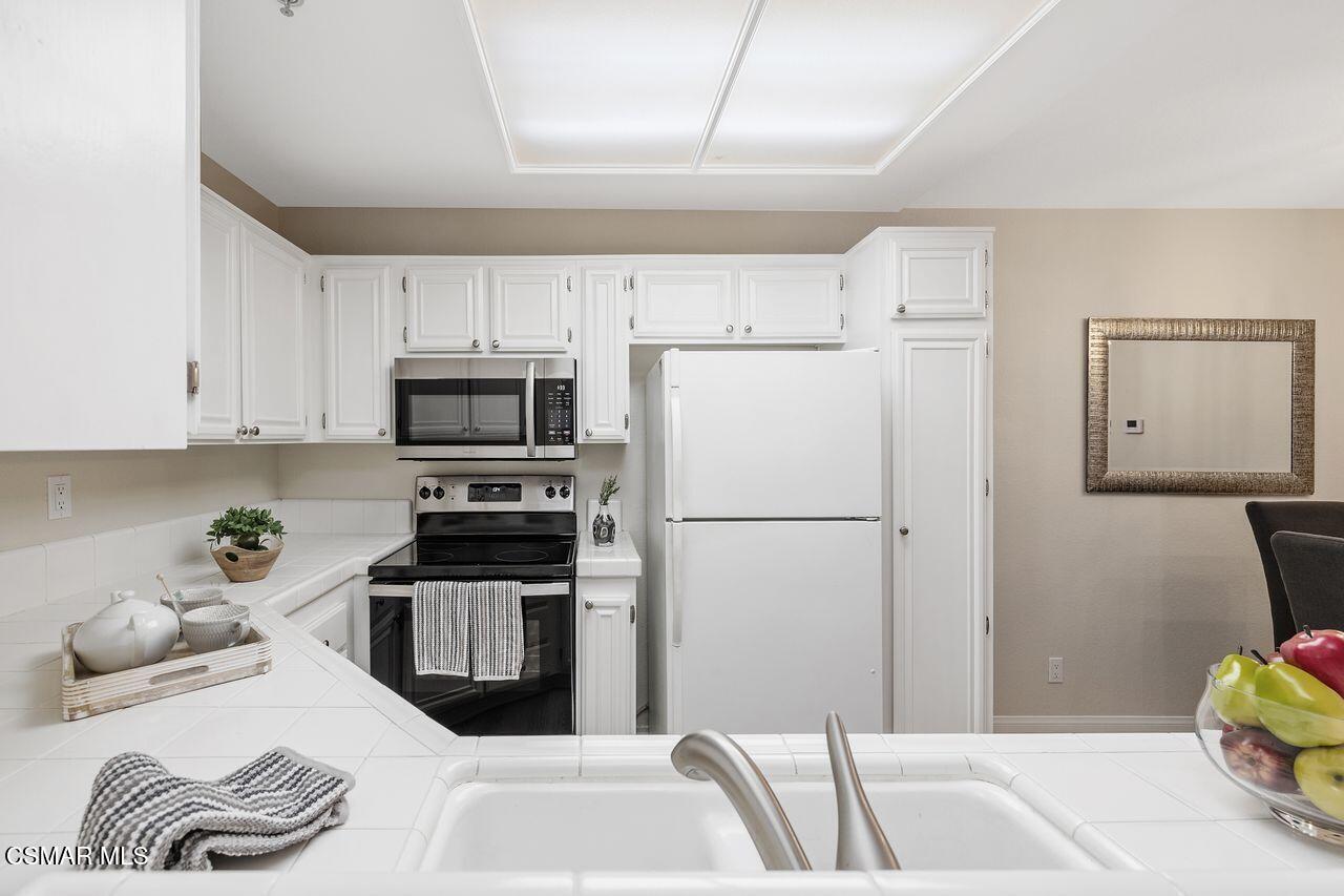 697 Sutton Crest Trail, Unit 302 Oak Park, CA 91377 - Photo 13 of 47 a kitchen with stainless steel appliances granite countertop a refrigerator sink and stove