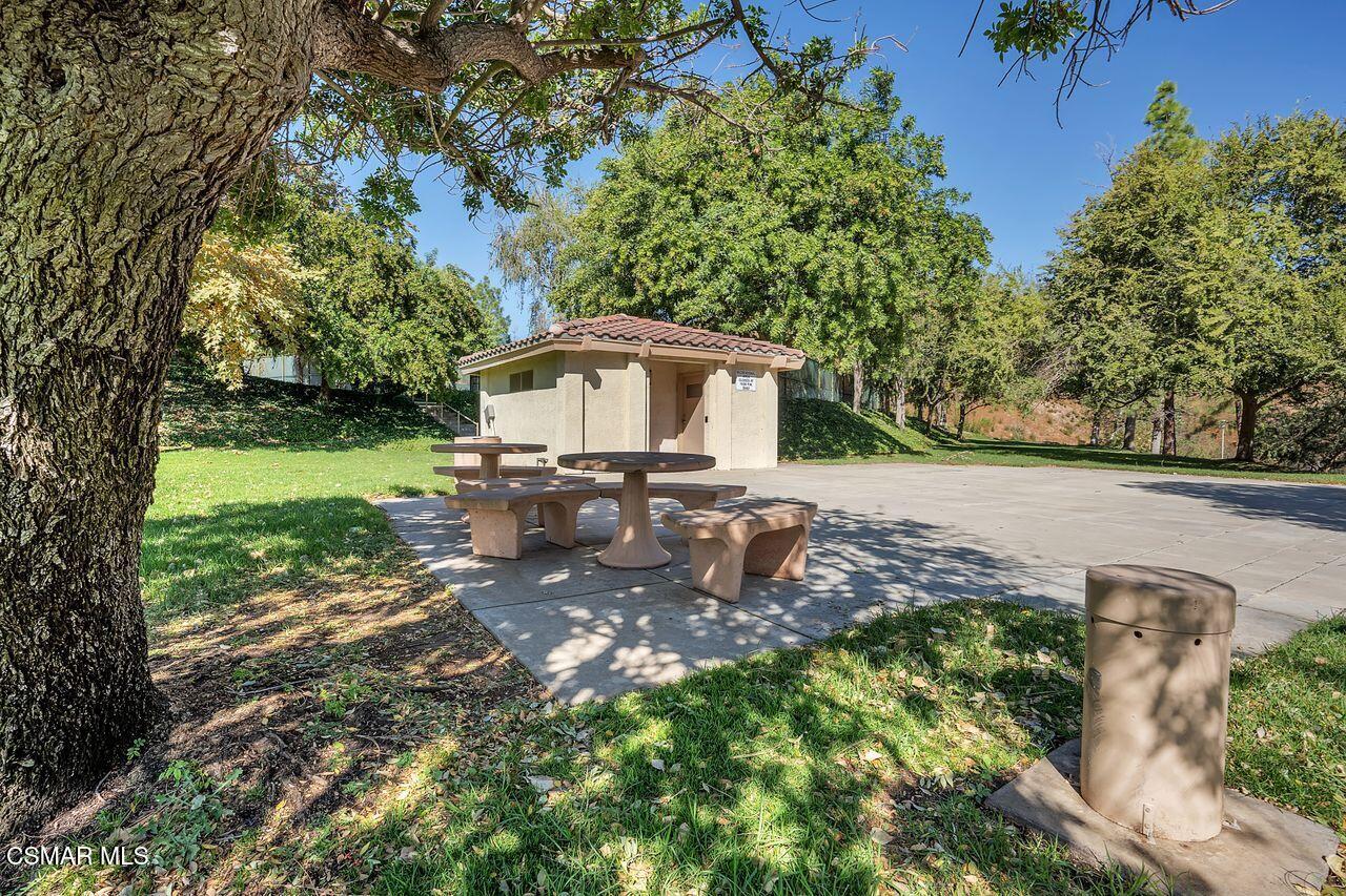 697 Sutton Crest Trail, Unit 302 Oak Park, CA 91377 - Photo 38 of 47 a view of a backyard with table and chairs plants and large trees