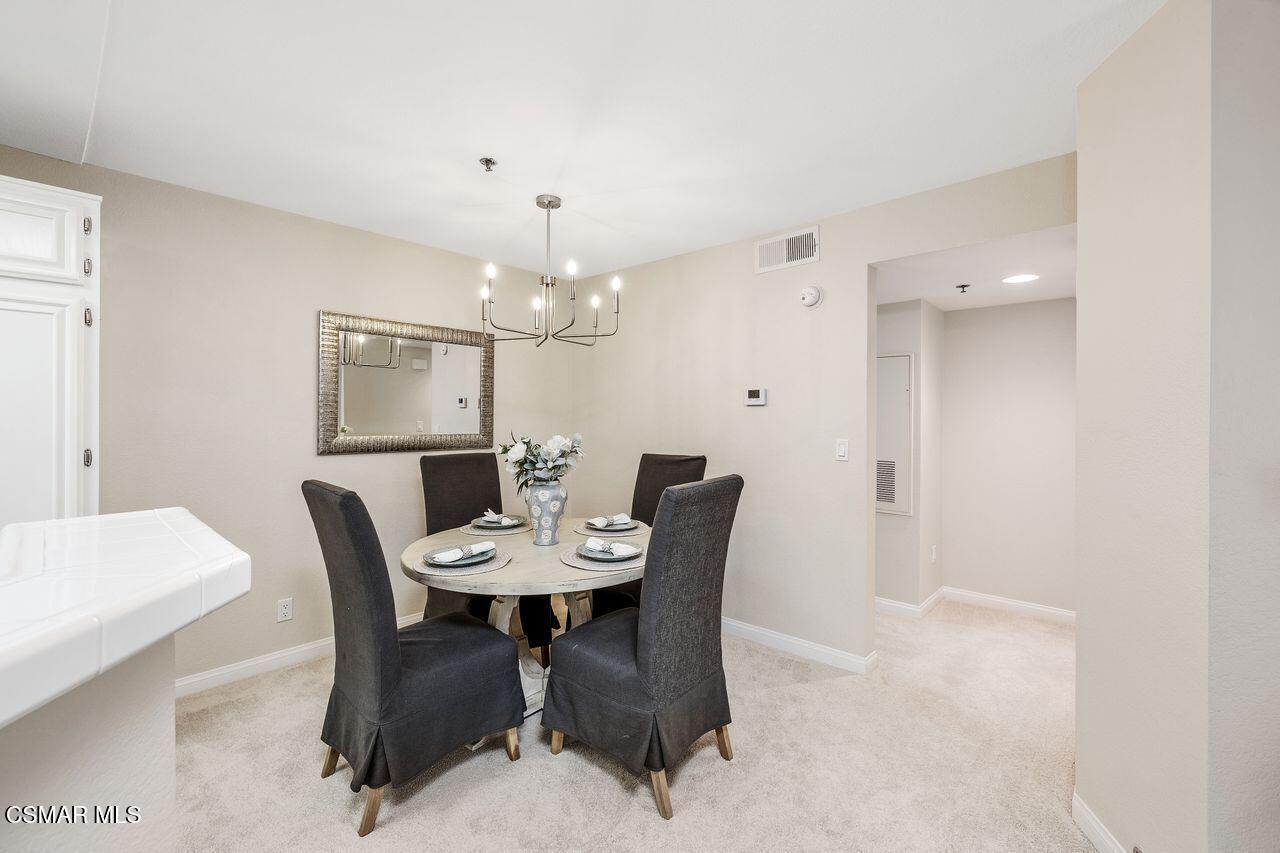 697 Sutton Crest Trail, Unit 302 Oak Park, CA 91377 - Photo 10 of 47 a view of a dining room with furniture and chandelier