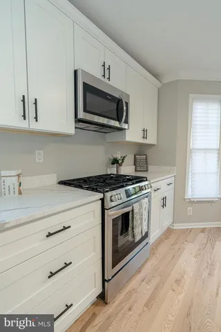 a kitchen with stainless steel appliances white cabinets and a stove top oven