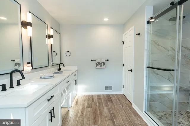 a spacious bathroom with a double vanity sink a large mirror and shower