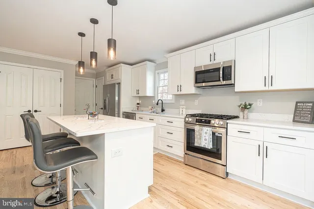 a kitchen with kitchen island a stove a sink and a microwave