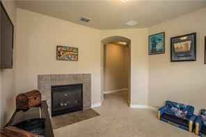 1409 Rosson Road Little Elm, TX 75068 - Photo 10 of 34 Recessed gas fireplace with a tiled surround, arched doorway, and neutral carpet flooring