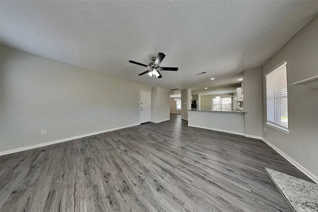 a view of empty room with wooden floor and ceiling fan