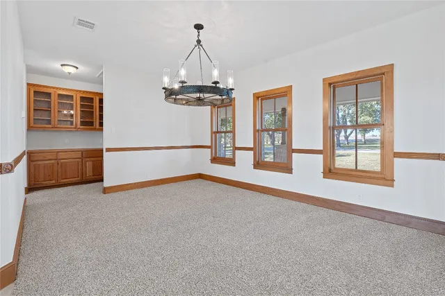 an empty room with chandelier and windows