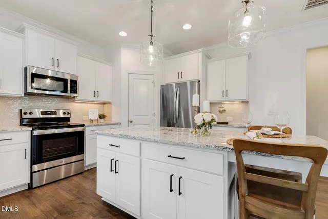 a kitchen with kitchen island white cabinets and stainless steel appliances