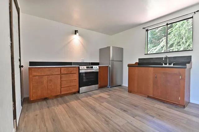 a kitchen with stainless steel appliances granite countertop a stove a refrigerator and a microwave oven with wooden floor