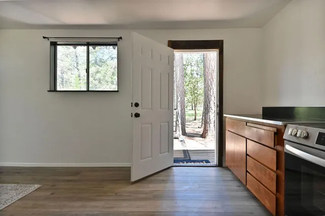 an empty room with wooden floor cabinet and windows