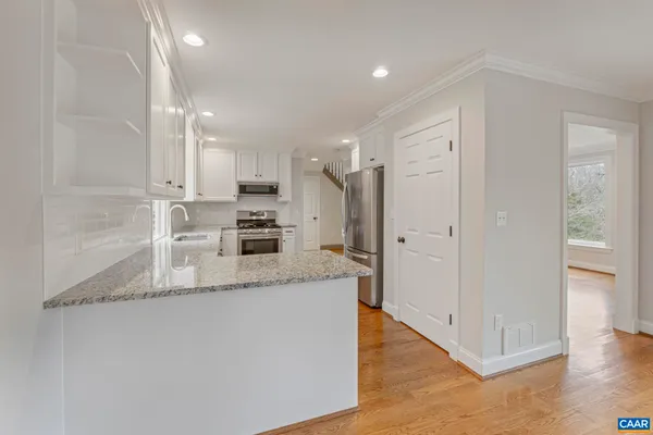 a kitchen with granite countertop white cabinets and stainless steel appliances