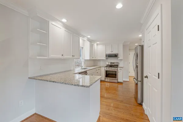 a kitchen with granite countertop white cabinets and white appliances