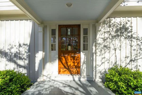 a view of an entryway with wooden floor leading to a furnished livingroom and windows