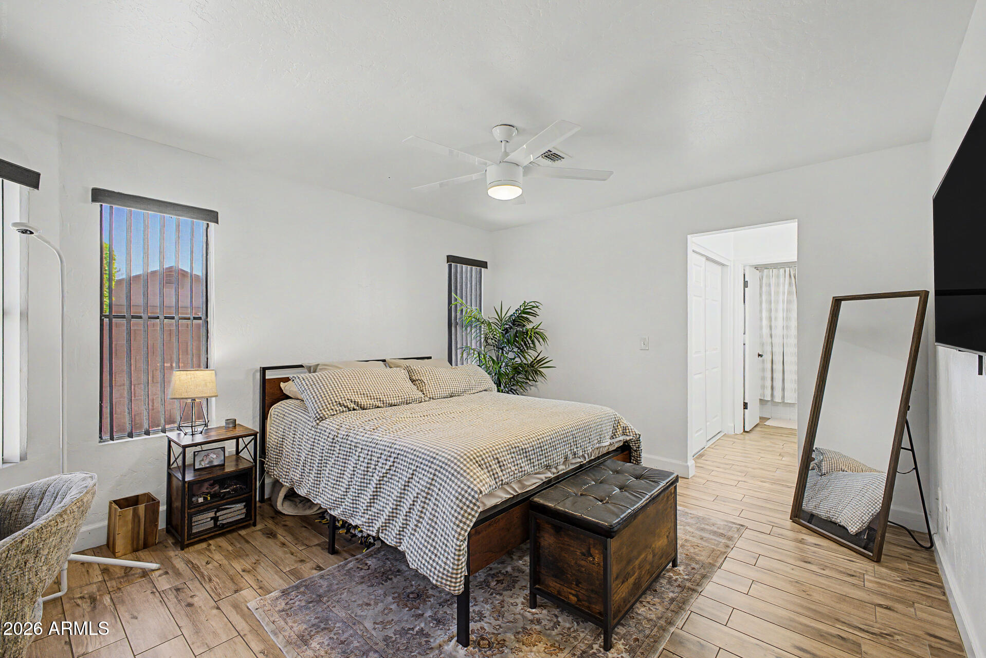4725 East Brown Road, Unit 70 Mesa, AZ 85205 - Photo 13 of 25 a bedroom with a bed a mirror on dresser and a wooden floor