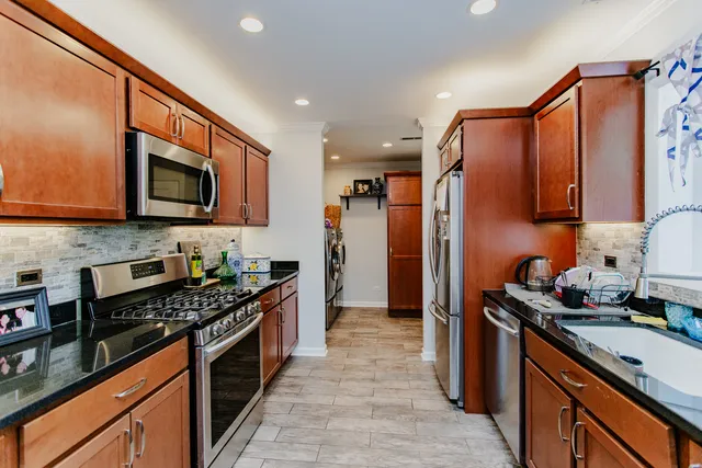 a kitchen with stainless steel appliances granite countertop a stove top oven a sink dishwasher and a refrigerator with wooden cabinets