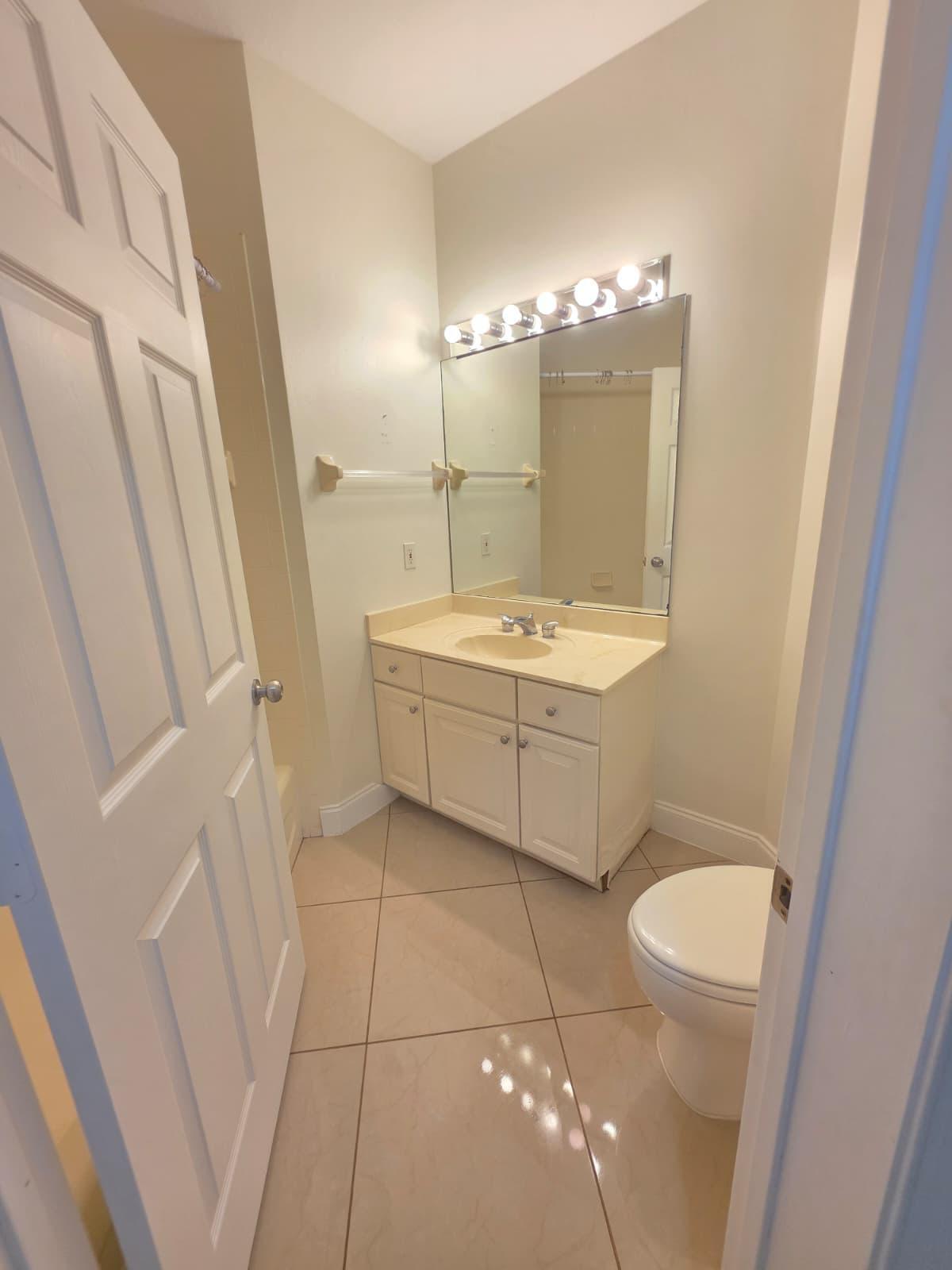 8262 Mulligan Circle, Unit 2613 SIDE B Port St. Lucie, FL 34986 - Photo 9 of 13 a bathroom with a sink a toilet a mirror and vanity