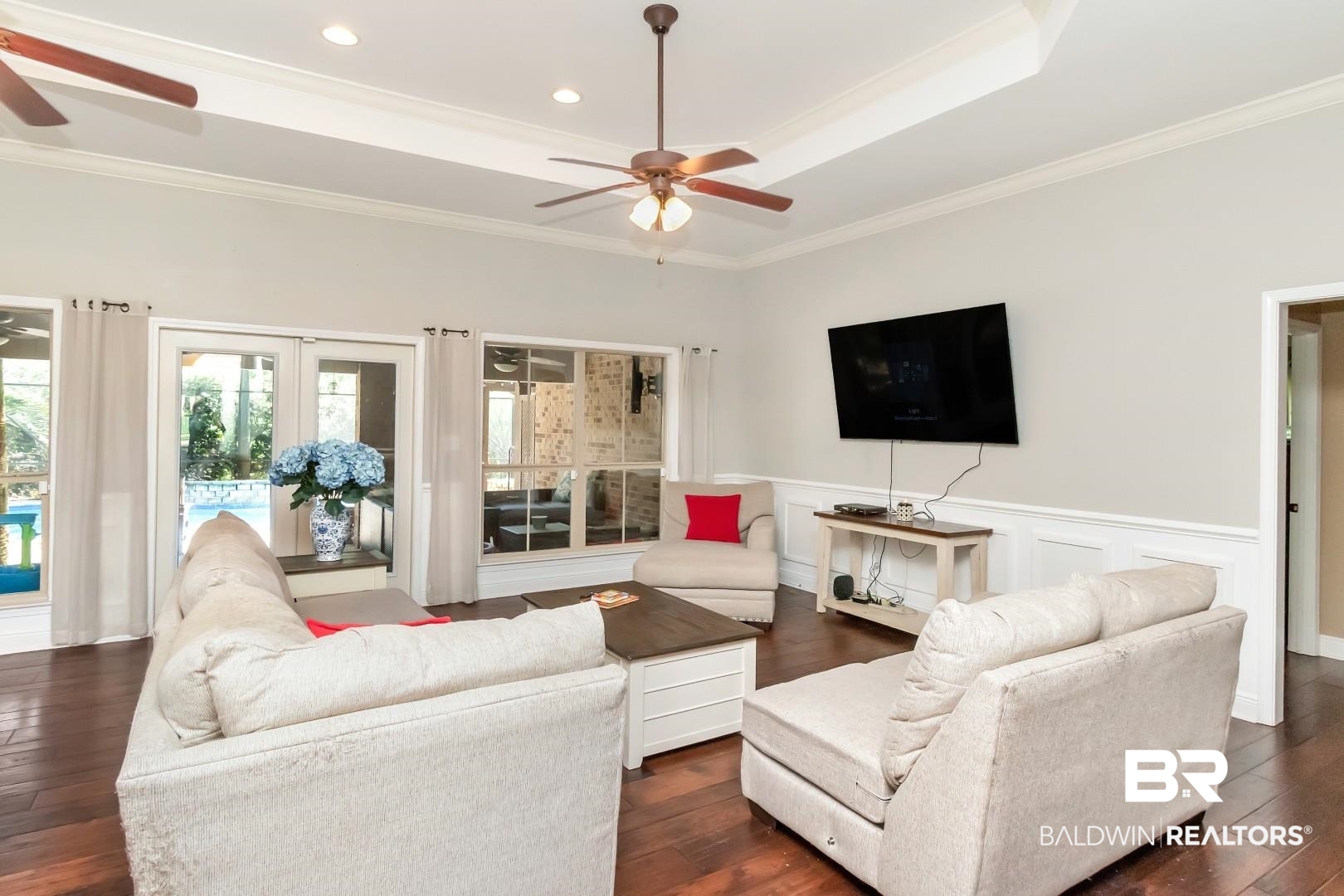 27890 Rileywood Drive Daphne, AL 36526 - Photo 7 of 49 Living area featuring crown molding, a raised ceiling, a ceiling fan, and a wainscoted wall