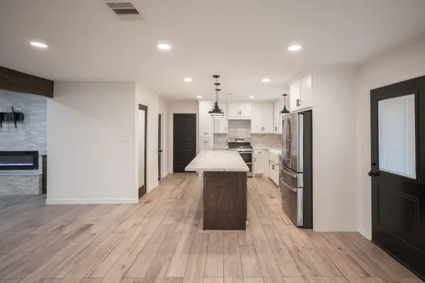a kitchen with stainless steel appliances a refrigerator sink and wooden floor