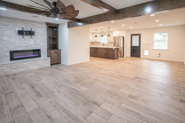 an empty room with wooden floor and a kitchen