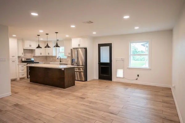 a large kitchen with stainless steel appliances kitchen island granite countertop a large counter top and a window