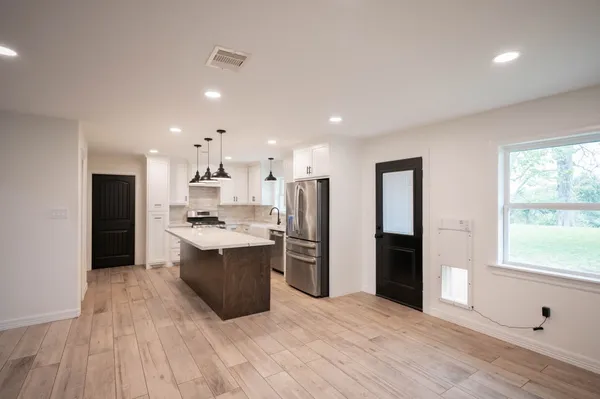 a large kitchen with stainless steel appliances kitchen island a large counter top and a refrigerator