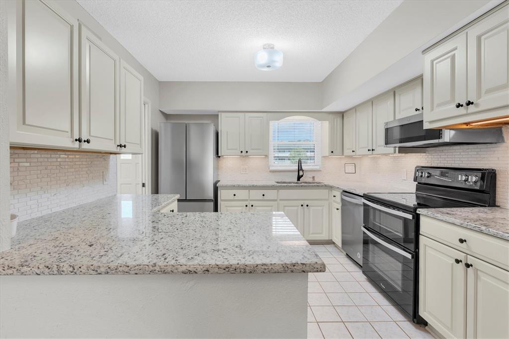 2417 Persian Drive, Unit 23 Clearwater, FL 33763 - Photo 13 of 48 a kitchen with granite countertop a sink stainless steel appliances and cabinets
