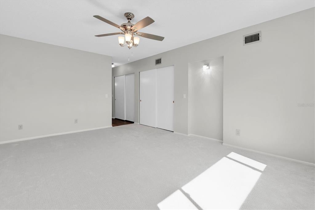2417 Persian Drive, Unit 23 Clearwater, FL 33763 - Photo 19 of 48 an empty room with a chandelier fan and windows