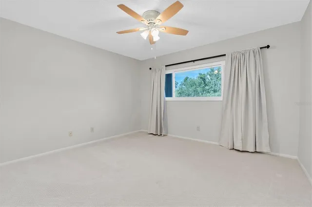an empty room with windows and fan