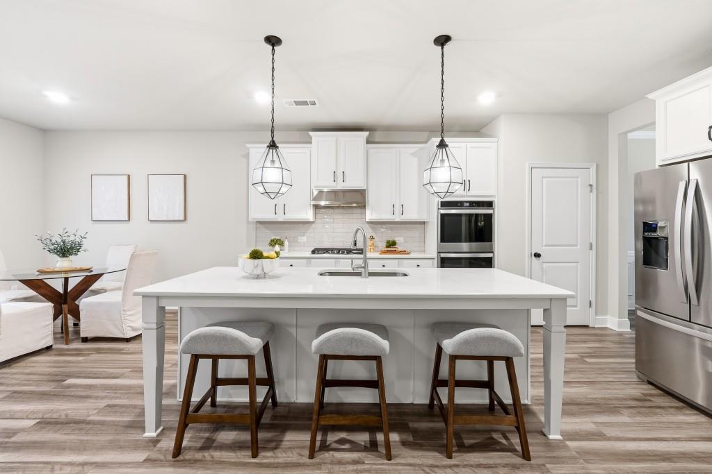 1849 Hanwoo Lane Powder Springs, GA 30127 - Photo 14 of 47 a kitchen with stainless steel appliances kitchen island granite countertop a dining table chairs and white cabinets