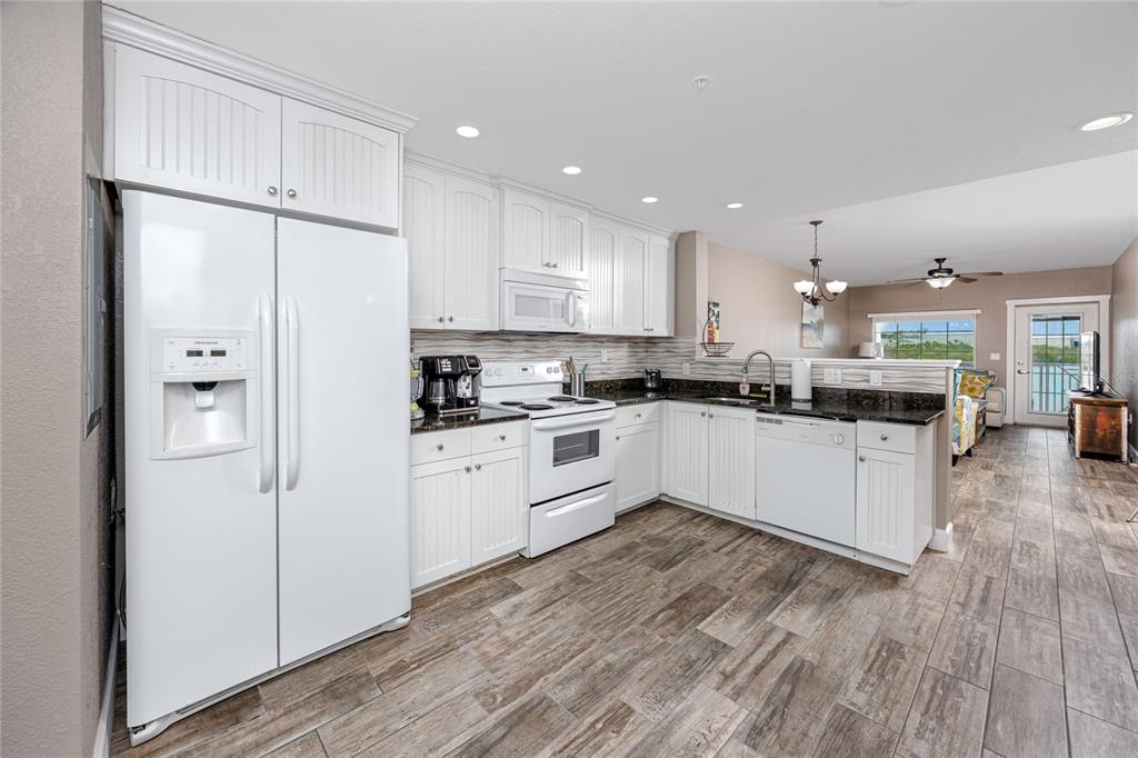 399 2nd Street, Unit 217 Indian Rocks Beach, FL 33785 - Photo 4 of 44 a kitchen with stainless steel appliances granite countertop a refrigerator a sink and white cabinets